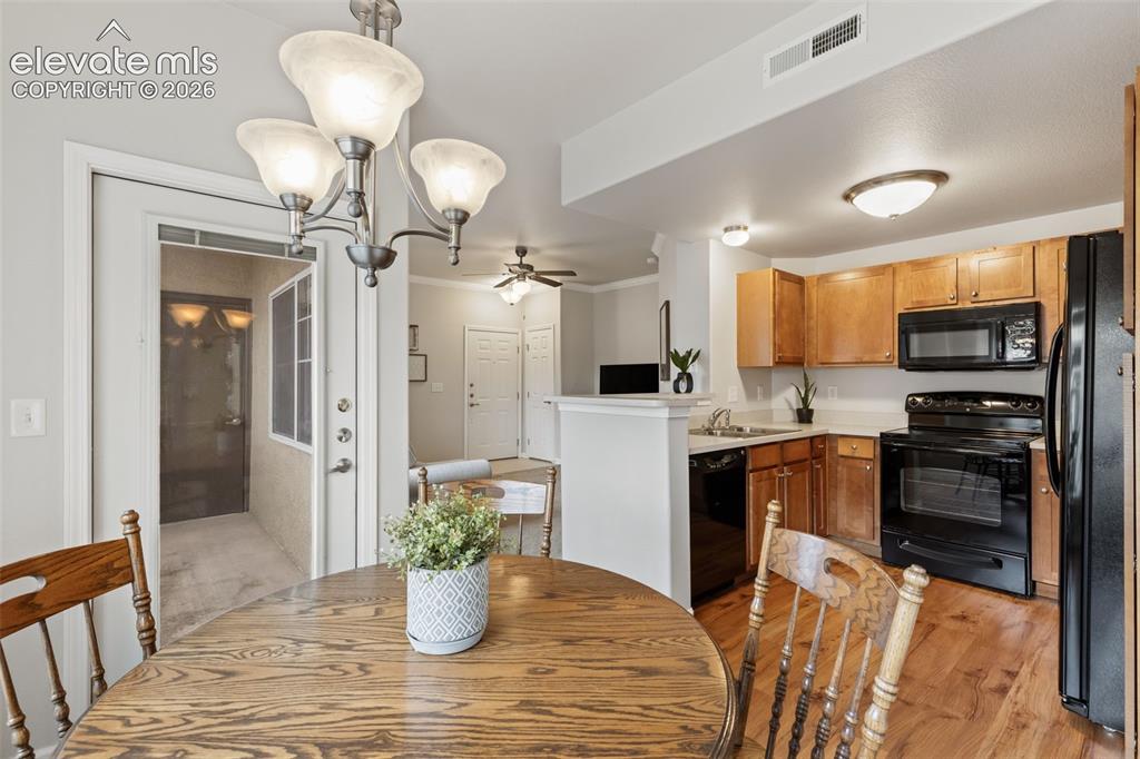 Image 9 of 31: Kitchen with wood-finish flooring, wood cabinetry, black appliances, and wh