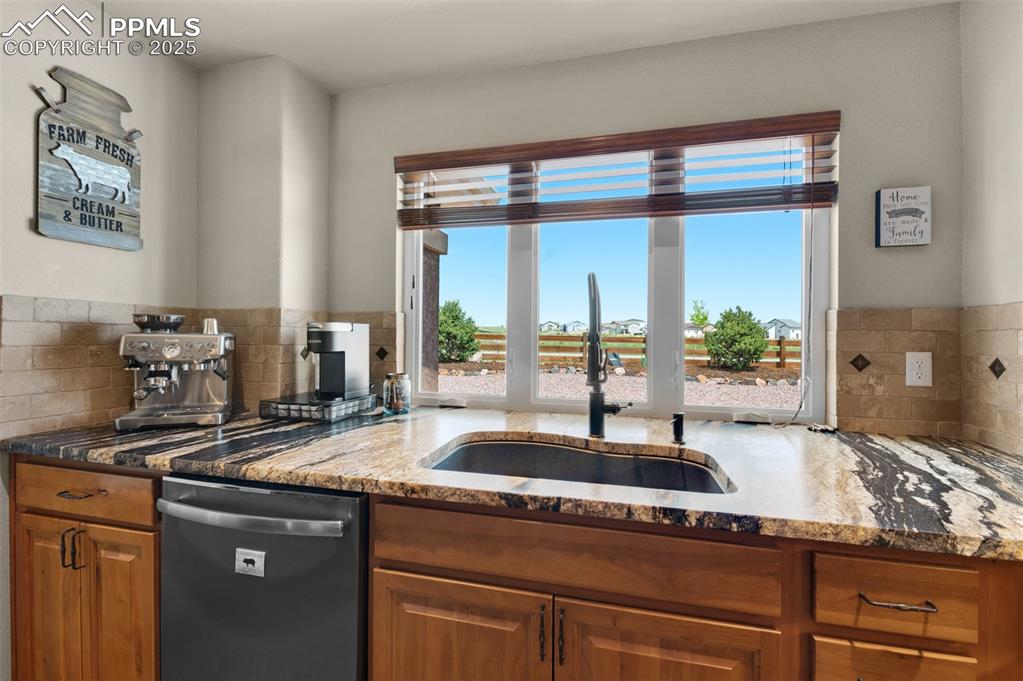 Image 15 of 48: Kitchen featuring dishwashing machine, plenty of natural light, stone count