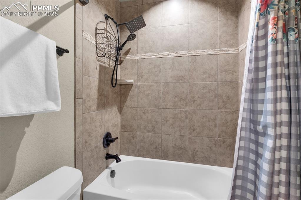 Image 38 of 48: Bathroom with shower / tub combo and a textured wall