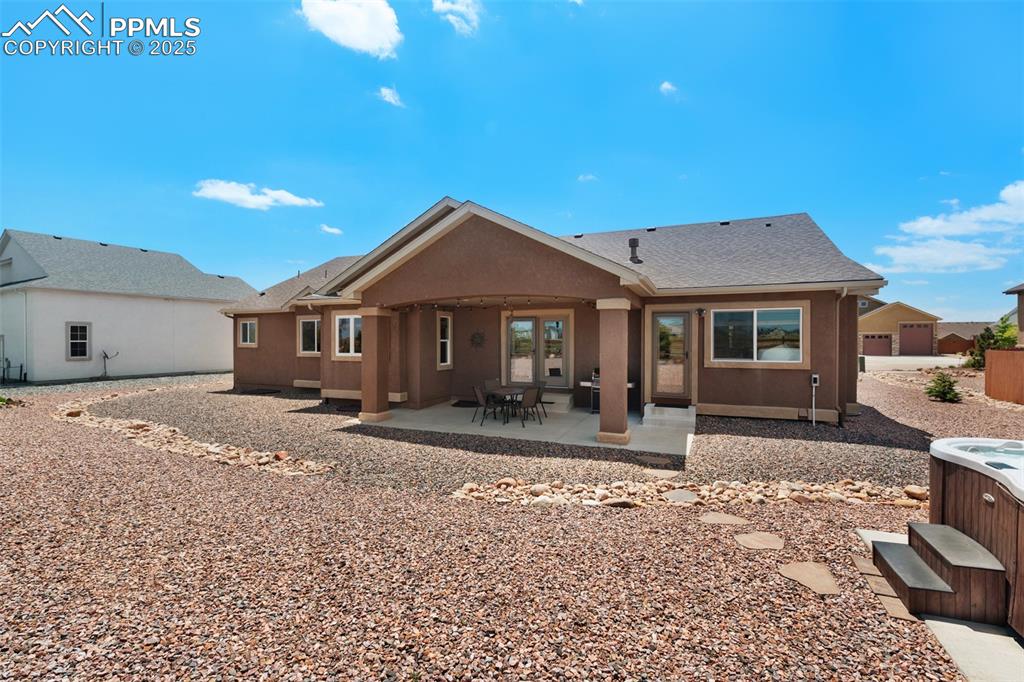 Image 40 of 48: Back yard with low maintenance xeric landscaping, covered patio and hot tub