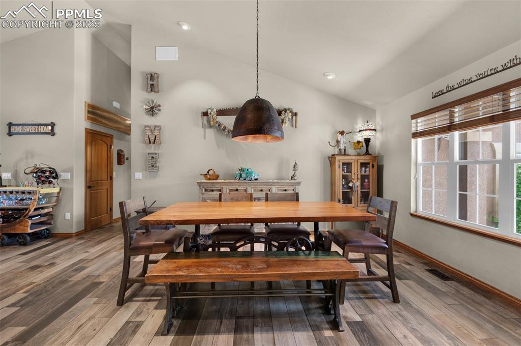 Image 6 of 48: Dining room featuring light wood-type flooring, high vaulted ceiling, and r