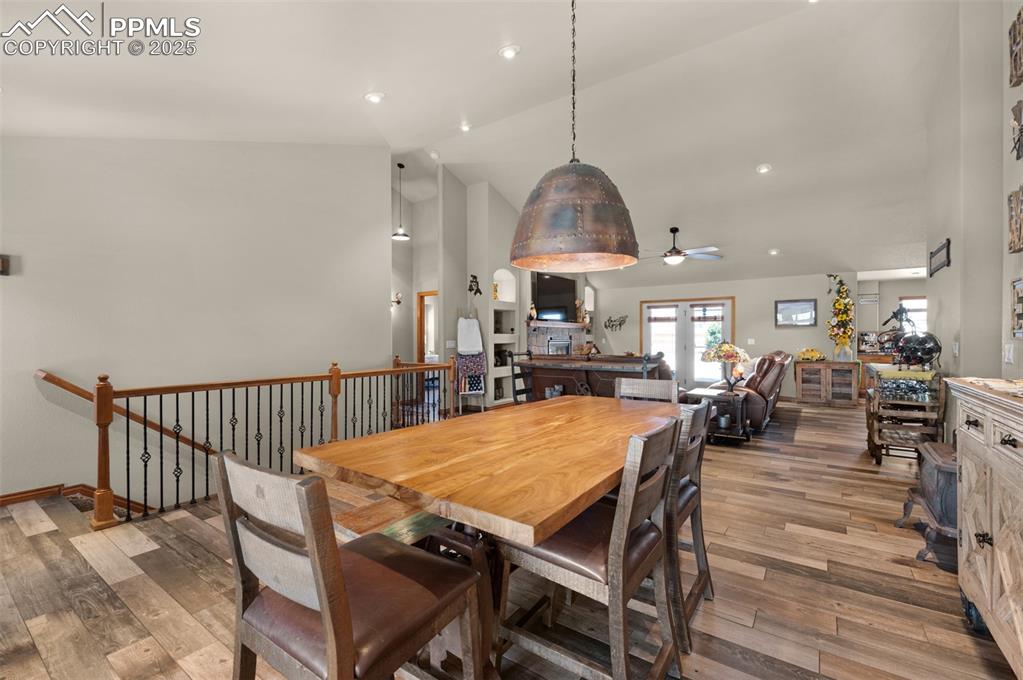 Image 7 of 48: Dining area with a ceiling fan, wood finished floors, high vaulted ceiling,