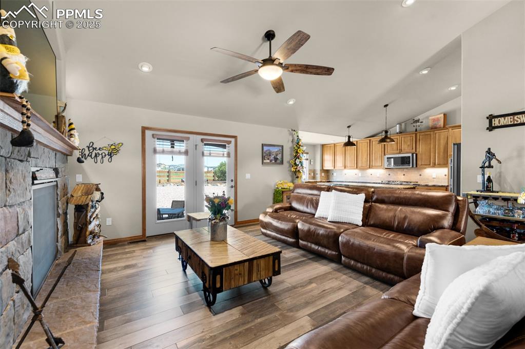 Image 8 of 48: Living room featuring vaulted ceiling, ceiling fan, a fireplace, wood finis