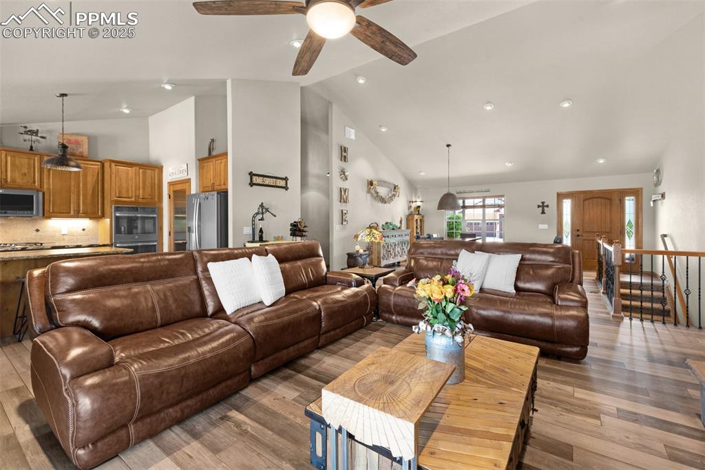 Image 9 of 48: Living area featuring high vaulted ceiling, a ceiling fan, light wood finis