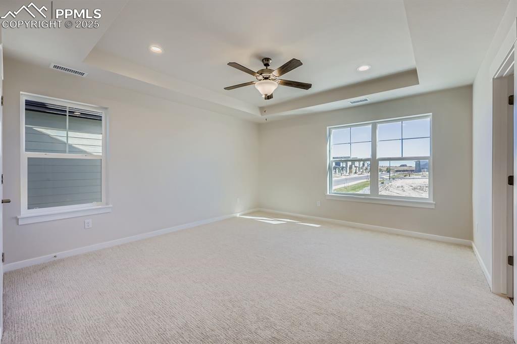Image 11 of 27: Unfurnished room featuring a tray ceiling, light colored carpet, recessed l