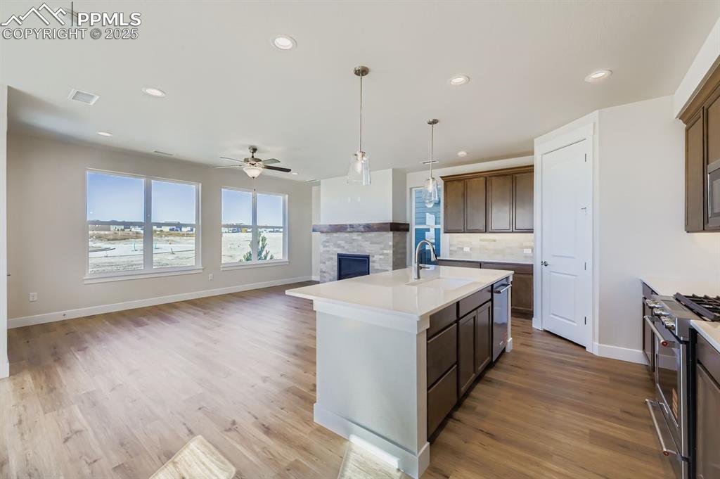 Image 7 of 27: Kitchen featuring pendant lighting, a kitchen island with sink, open floor 
