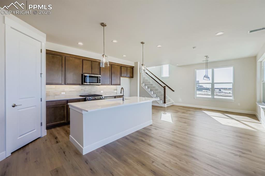 Image 8 of 27: Kitchen featuring decorative light fixtures, decorative backsplash, a kitch