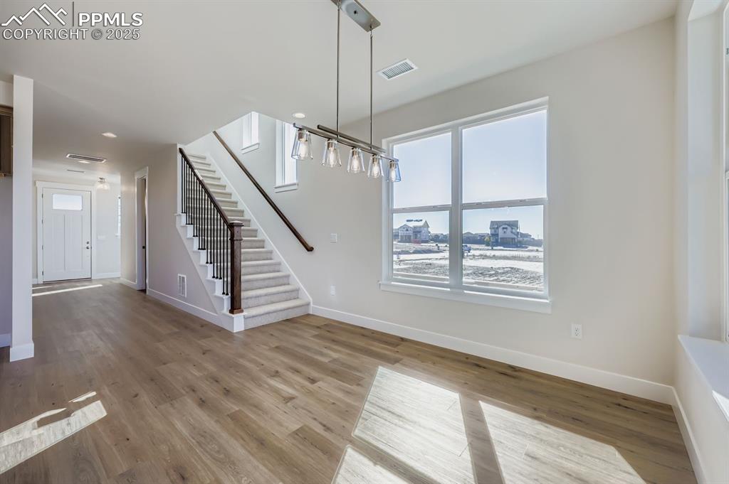 Image 9 of 27: Unfurnished dining area featuring stairway, light wood-style floors, and re
