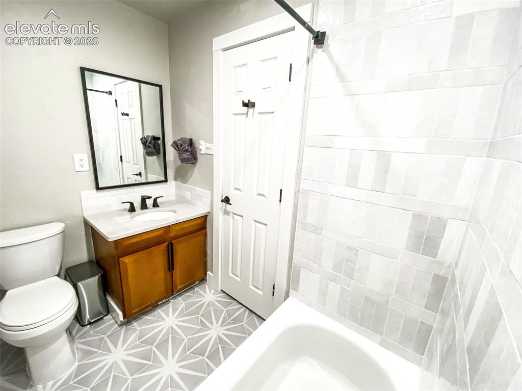 Image 16 of 29: Bathroom featuring a white bathtub, patterned floor tile, wood-finish vanit