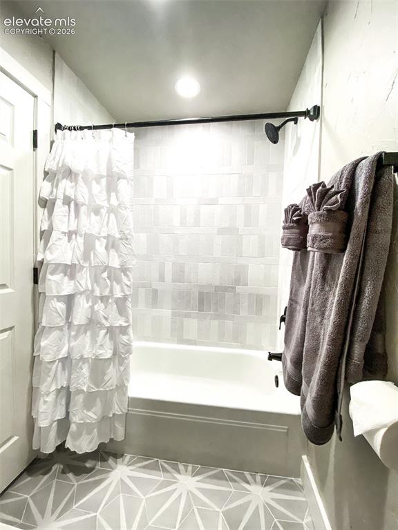 Image 17 of 29: Bathroom featuring a white bathtub, gray rectangular tile surround, matte b