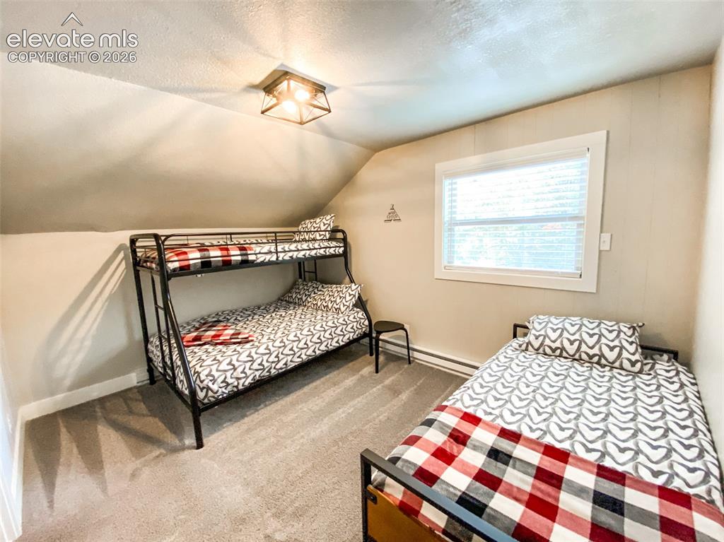 Image 18 of 29: Bedroom featuring sloped ceilings, recessed window with blinds, and light g