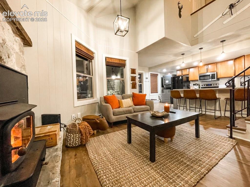 Image 23 of 29: Open-concept living space featuring wood-finish flooring, a stone fireplace