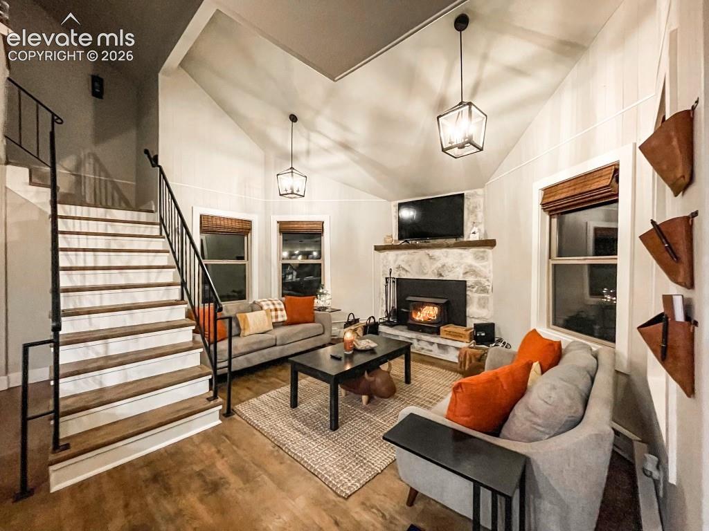 Image 24 of 29: Vaulted ceiling living area featuring wood-finish flooring and a stone-clad