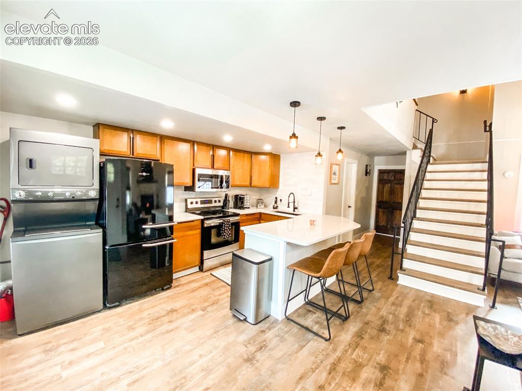 Image 4 of 29: Open-concept kitchen featuring wood-finish flooring, a white countertop isl
