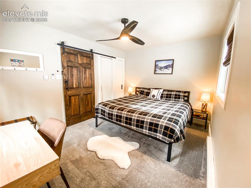 Image 8 of 29: Bedroom featuring a rustic wood barn door, gray wall paint, and recessed li