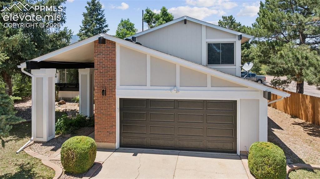 Image 1 of 42: Exterior featuring a two-car garage, brick facade accents, and mature lands