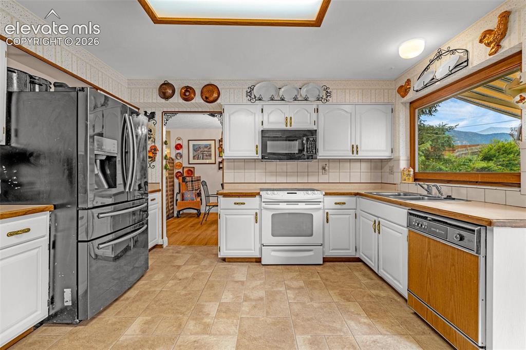 Image 14 of 45: U-shaped kitchen featuring white cabinetry, light countertops, integrated a
