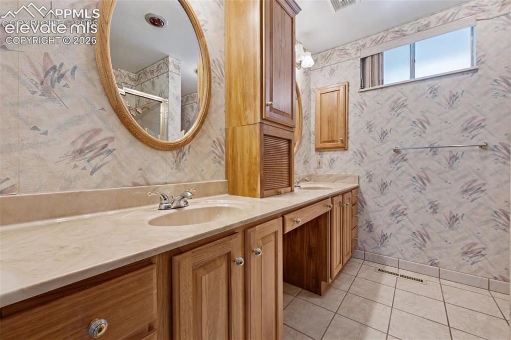 Image 17 of 42: Dual vanity with integrated sinks, wood cabinetry, and a full-width counter