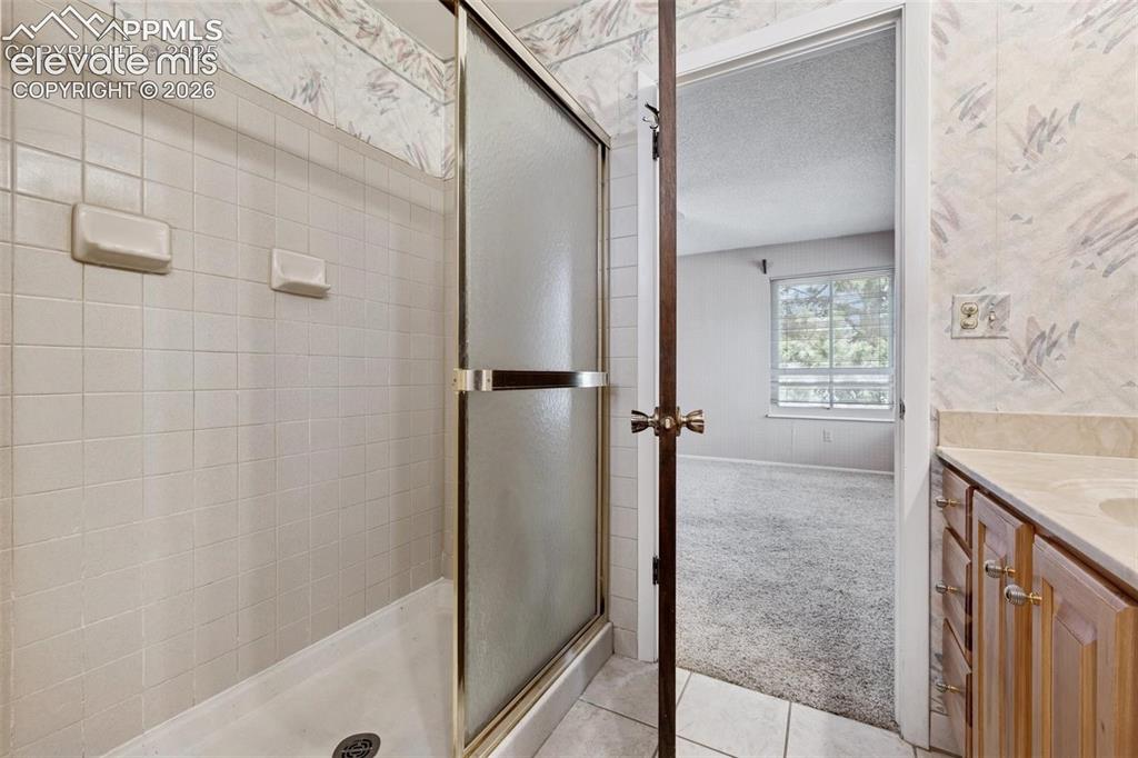 Image 18 of 42: Tile shower with a sliding glass enclosure