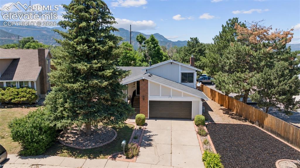Image 2 of 42: Split-level residence featuring a two-car garage, concrete driveway, and ma