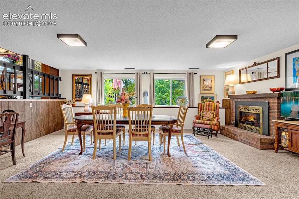Image 26 of 45: Spacious room featuring a brick-surround fireplace with a metal insert, woo