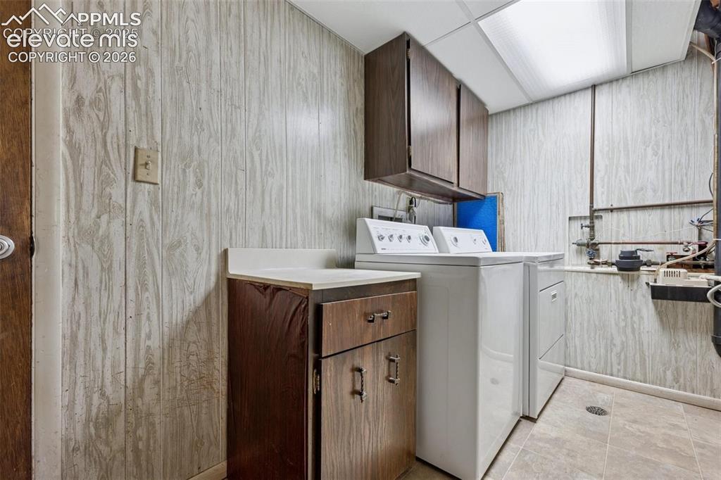 Image 28 of 42: Utility room featuring wood-panel walls, tiled flooring, built-in cabinetry