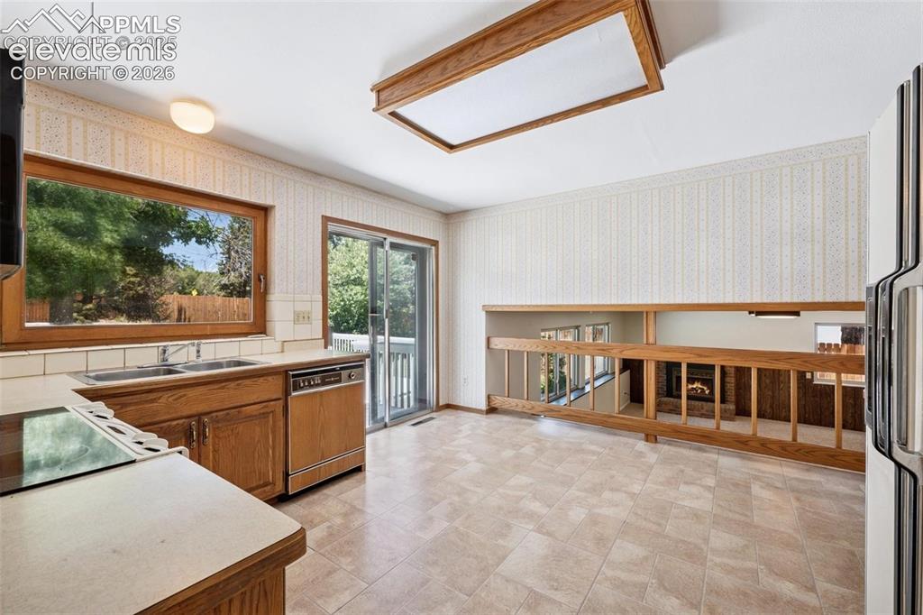 Image 7 of 42: Kitchen featuring wood-finish cabinetry, built-in dishwasher, and a double