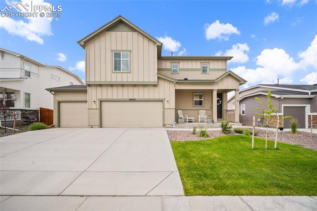 Caption: Craftsman house featuring board and batten siding, a garage, a porch, and driveway.