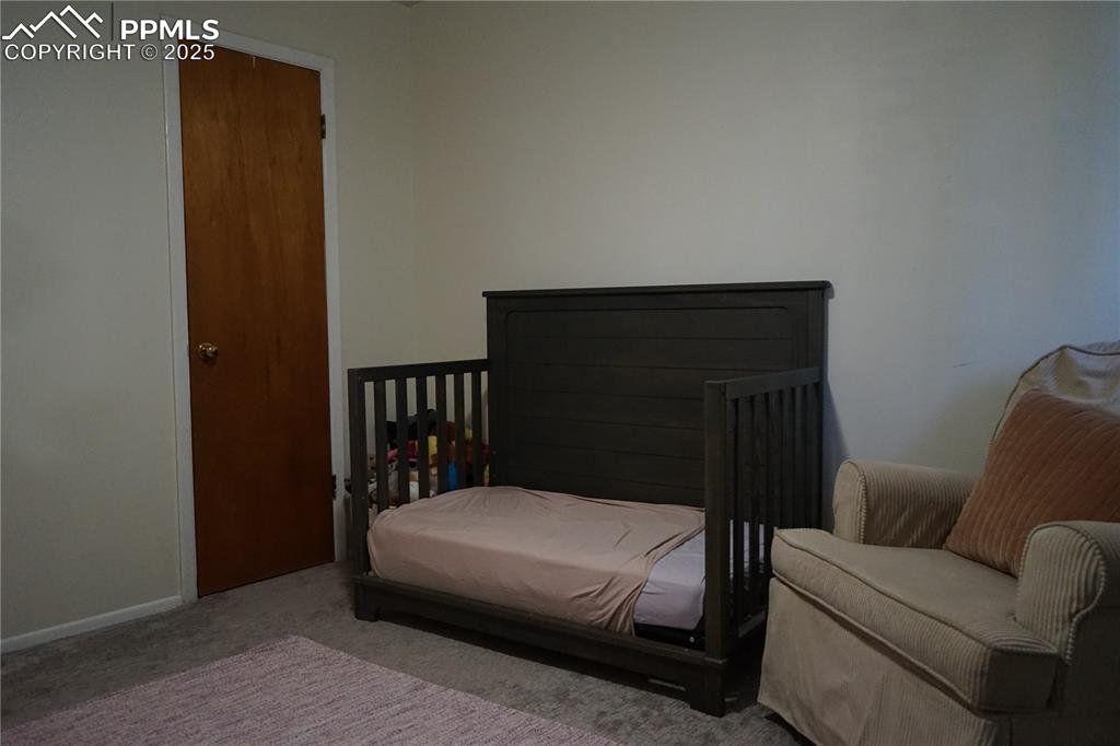 Image 15 of 22: Carpeted bedroom featuring a nursery area and baseboards