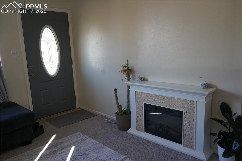 Image 2 of 22: Carpeted foyer with a stone fireplace and baseboards