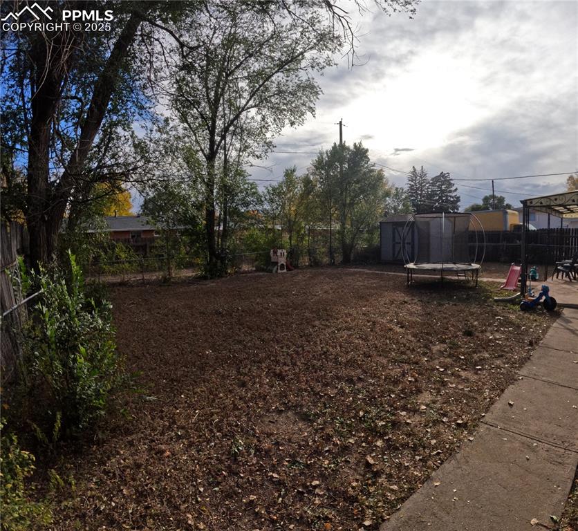 Image 21 of 22: Fenced backyard with a trampoline