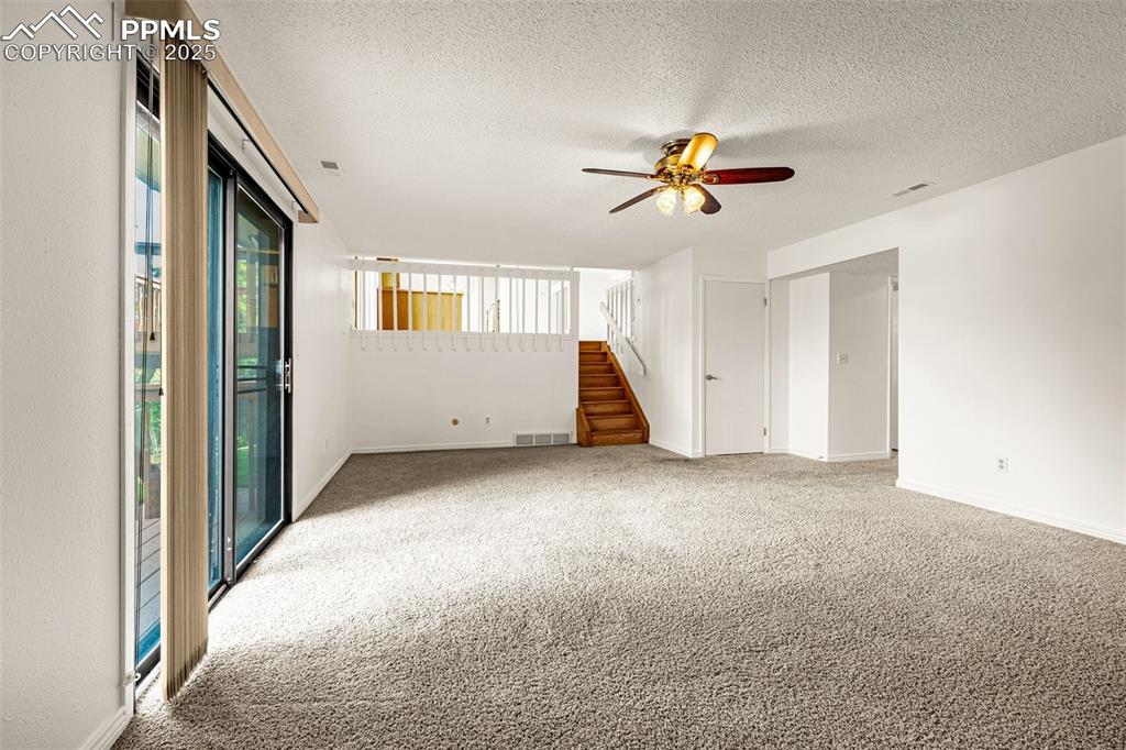 Image 25 of 47: Empty room with light colored carpet, a textured ceiling, ceiling fan, and 