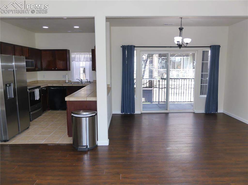 Image 10 of 33: Kitchen featuring dark brown cabinetry, an inviting chandelier, light wood
