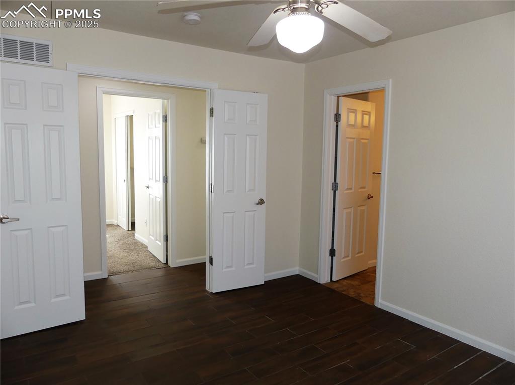 Image 15 of 33: Primary bedroom with baseboards, a ceiling fan, dark wood finished floors,