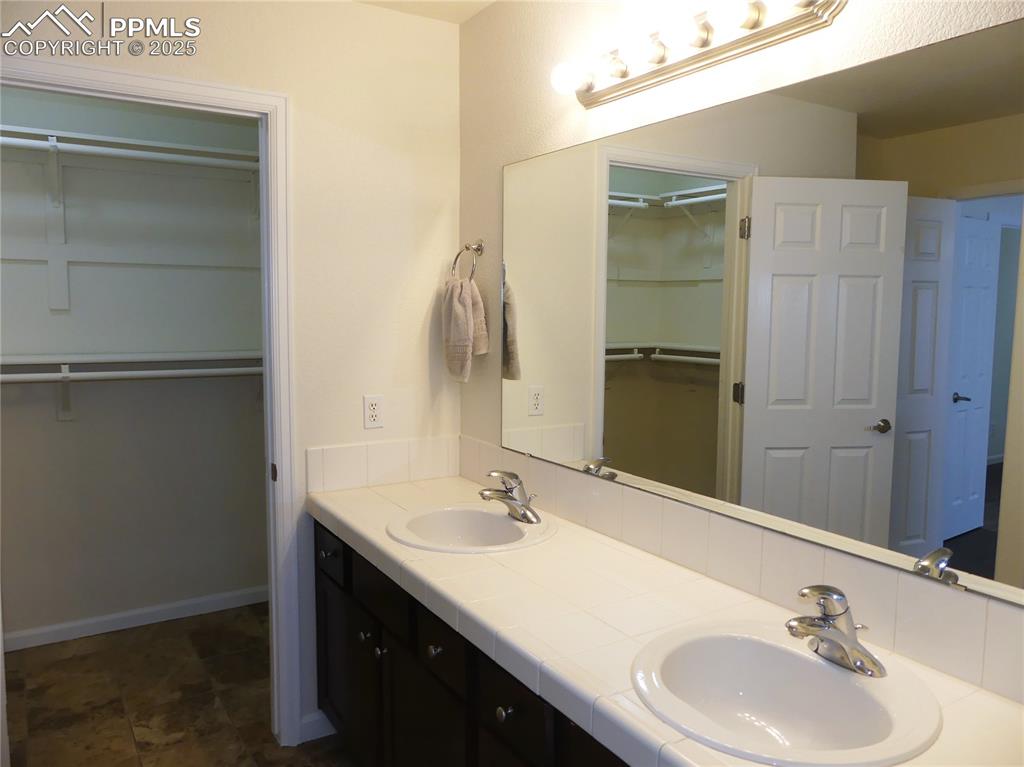 Image 18 of 33: Bathroom featuring double vanity, a sink, and a spacious closet