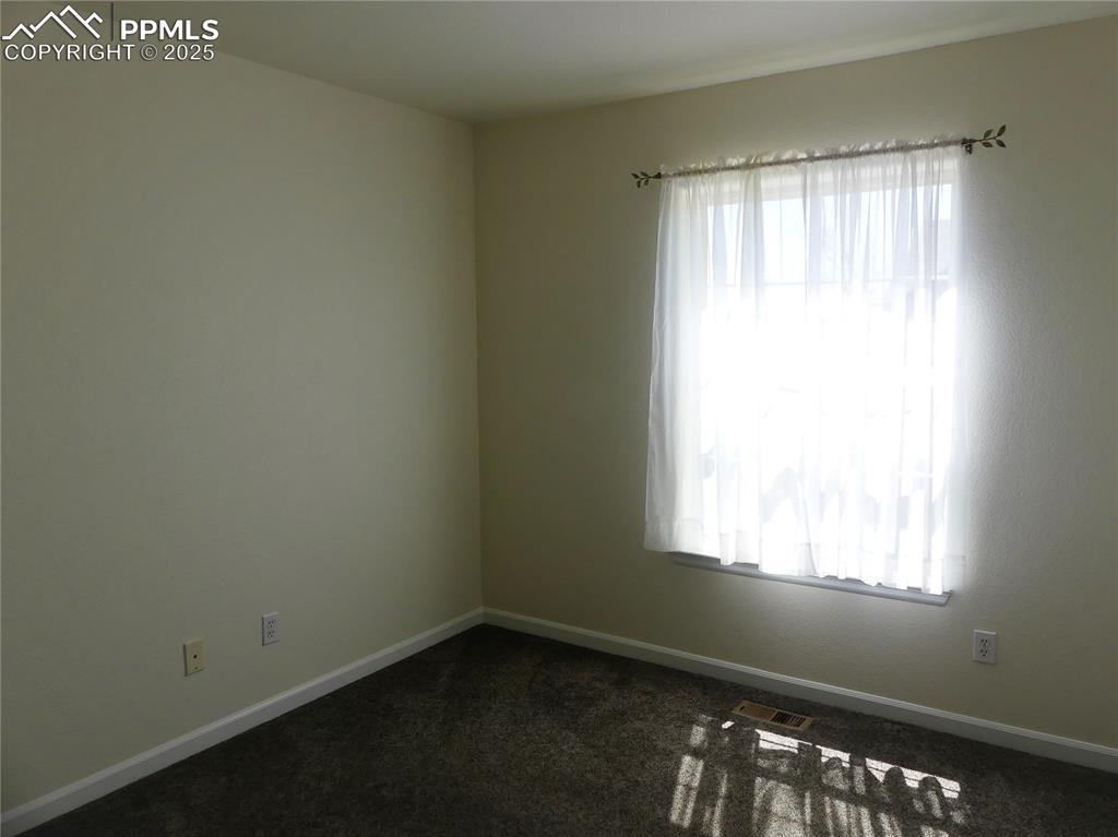 Image 19 of 33: Unfurnished room with baseboards, visible vents, and dark carpet
