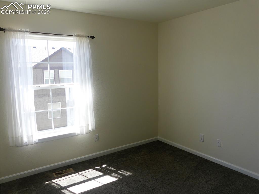 Image 21 of 33: Empty room featuring visible vents, baseboards, and dark carpet
