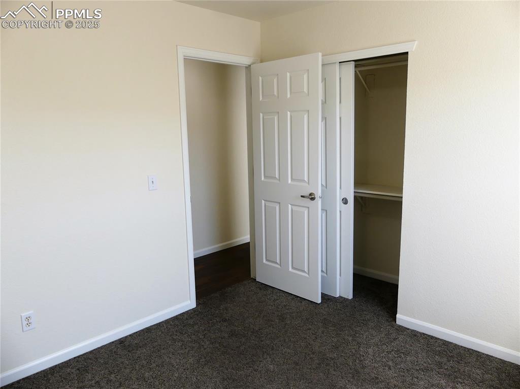 Image 22 of 33: Unfurnished bedroom with baseboards, a closet, and dark carpet