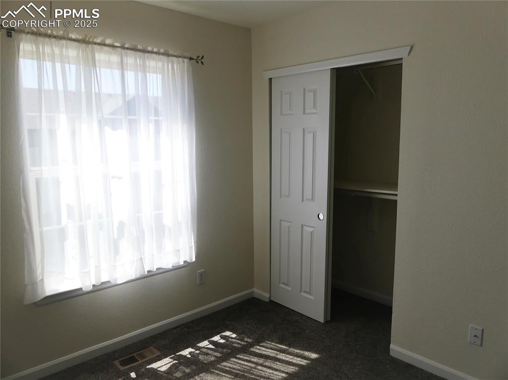 Image 23 of 33: Unfurnished bedroom with baseboards, a closet, dark colored carpet, and vis