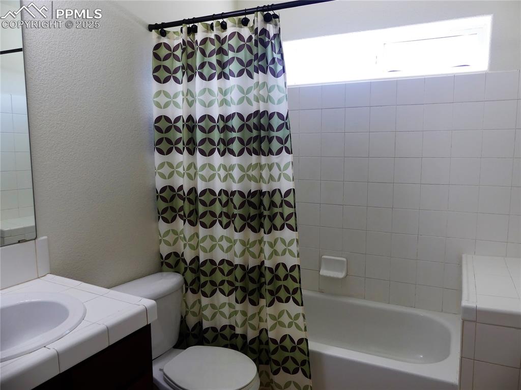 Image 24 of 33: Bathroom with vanity, a textured wall, toilet, and shower / bath combinatio