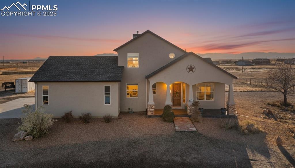 Caption: View of front of property featuring stucco siding, a porch, and a shingled roof