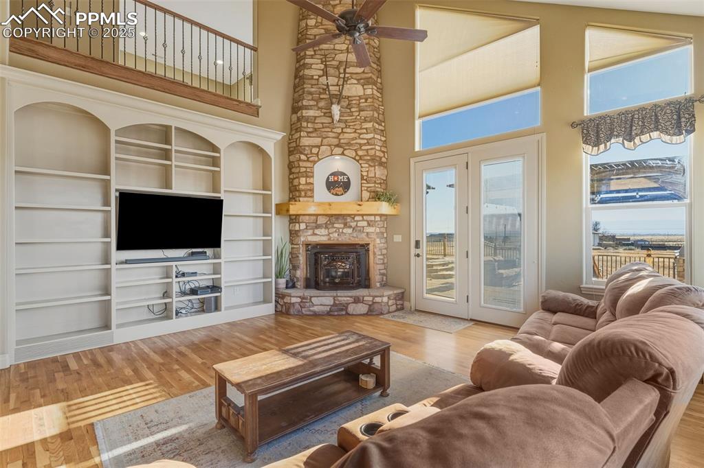 Image 12 of 49: Living area featuring a high ceiling, wood finished floors, a stone firepla