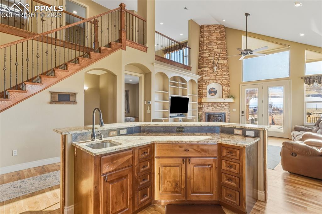 Image 14 of 49: Kitchen with brown cabinets, high vaulted ceiling, open floor plan, a cente