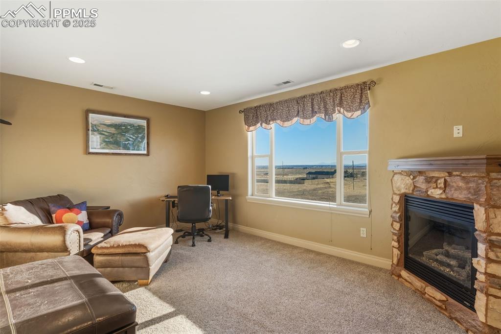 Image 21 of 49: Living room featuring a desk, carpet flooring, a stone fireplace, and reces