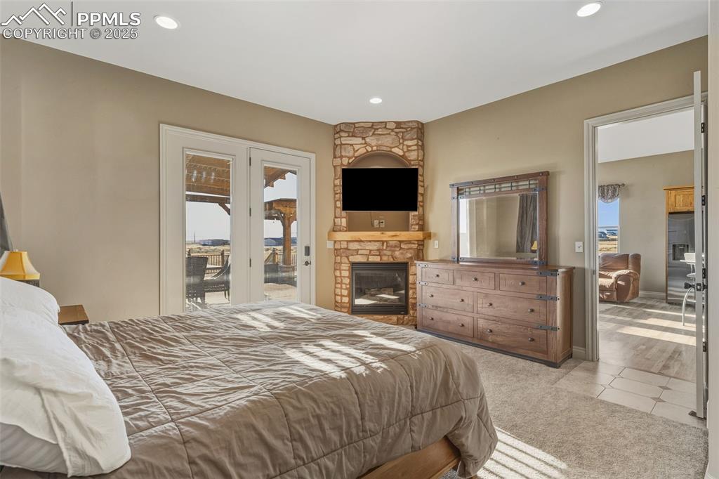 Image 23 of 49: Bedroom featuring access to outside, a large fireplace, carpet flooring, st
