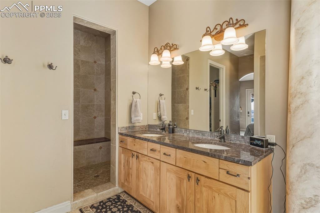 Image 26 of 49: Bathroom featuring double vanity and tiled shower