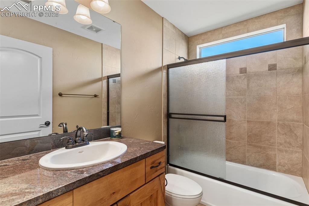 Image 30 of 49: Full bath featuring vanity and shower / bath combination with glass door
