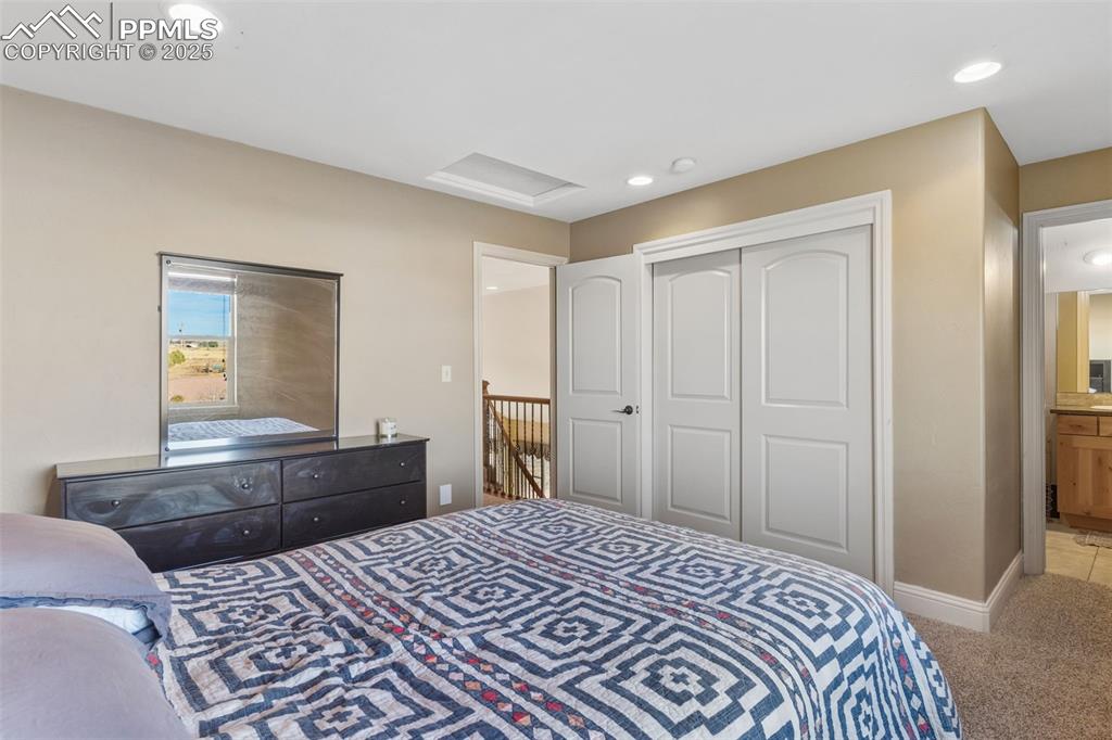 Image 32 of 49: Bedroom featuring light carpet, attic access, a closet, and recessed lighti