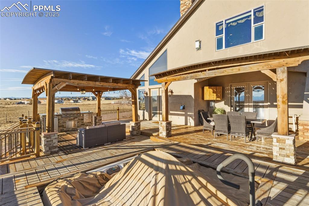 Image 39 of 49: View of patio with an outdoor kitchen, outdoor dining space, a wooden deck,