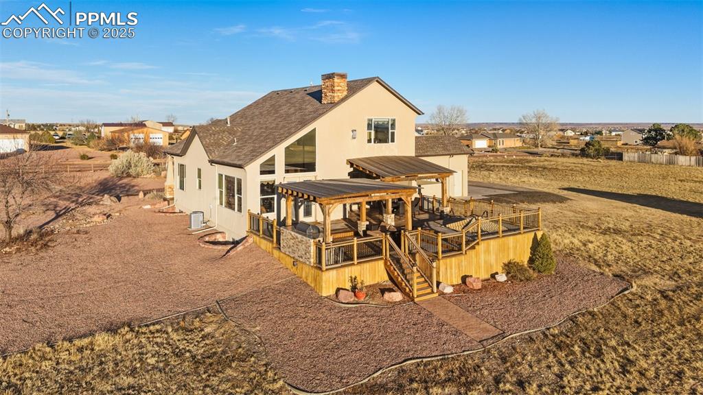 Image 41 of 49: Rear view of property with a wooden deck, a chimney, roof with shingles, st